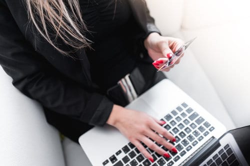 Kobieta siedzi przy laptopie i robi zakupy online